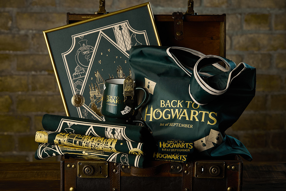 An open Hogwarts trunk with green and gold Back to Hogwarts items