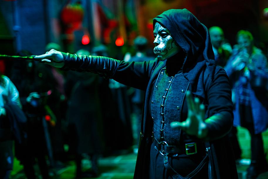 A Death Eater standing in the Great Hall and pointing their wand